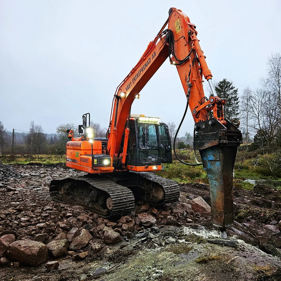 Orange grävmaskin som gräver ut mark